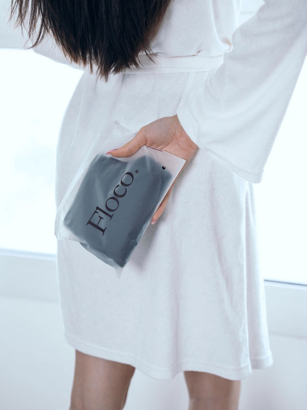 Person holding a gray pouch with 'FLOCO' branding against a white background